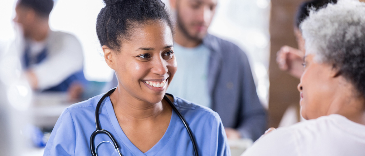 Health care provider smiles as she speaks with a female patient