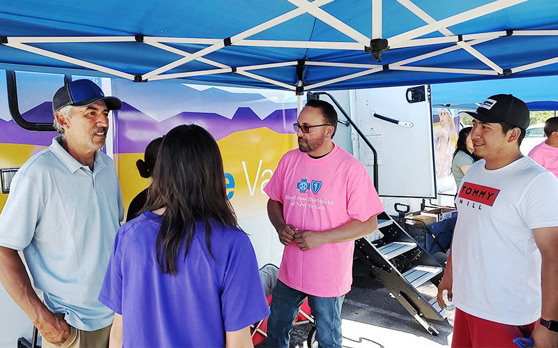 Outreach workers stand under a tent