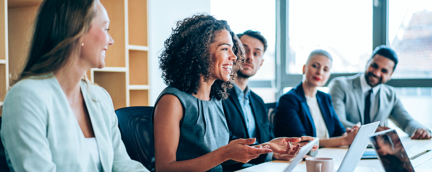 A woman smiles while speaking at a business meeting